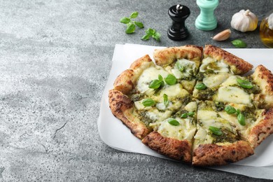 Photo of Delicious pizza with pesto, cheese and basil on grey table. Space for text