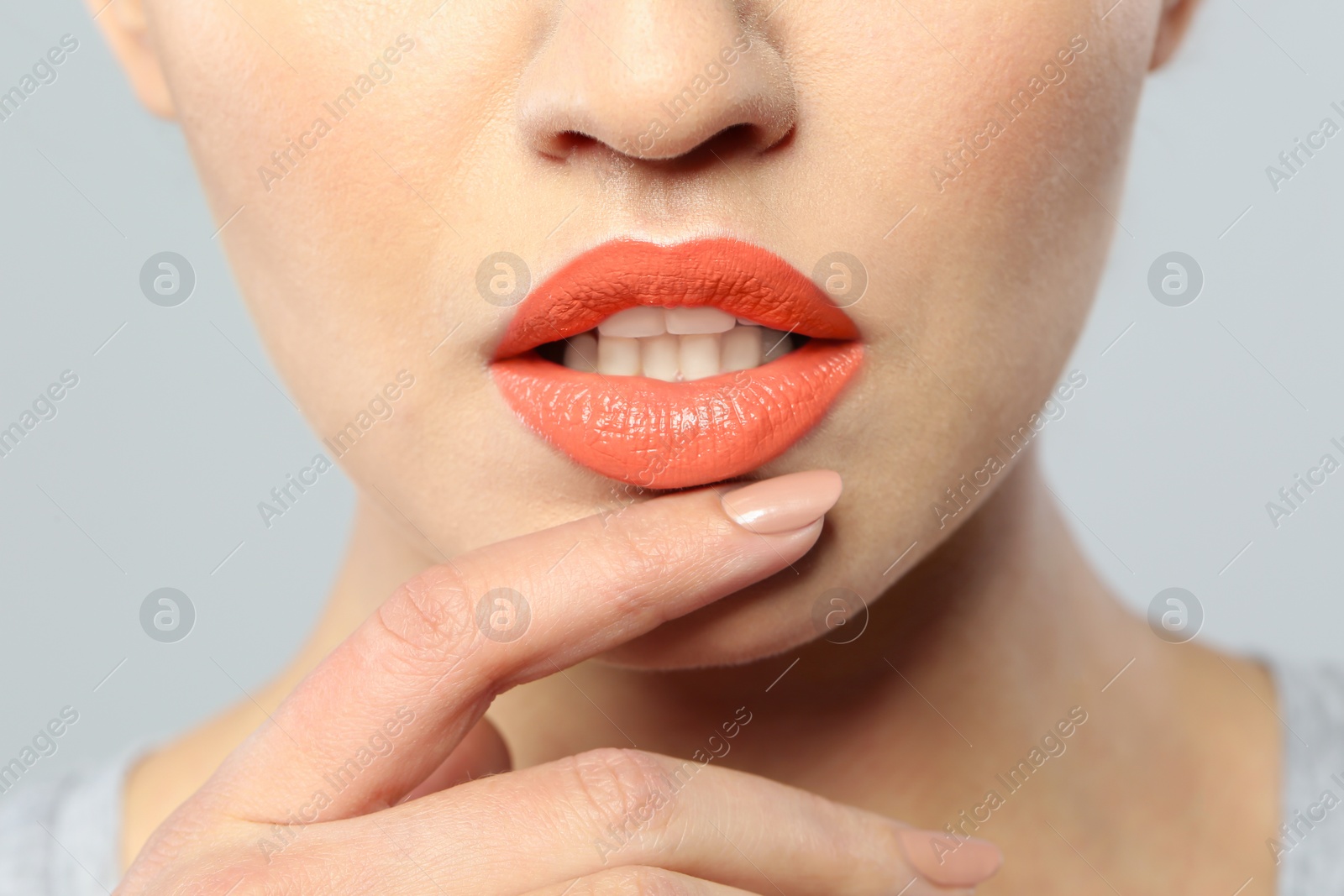 Photo of Young woman wearing beautiful lipstick on gray background, closeup