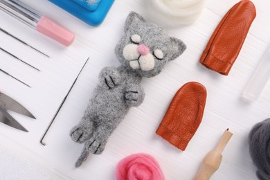 Felted cat, wool and different tools on white wooden table, flat lay