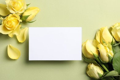 Photo of Beautiful yellow roses, petals and blank card on light olive background, flat lay. Space for text