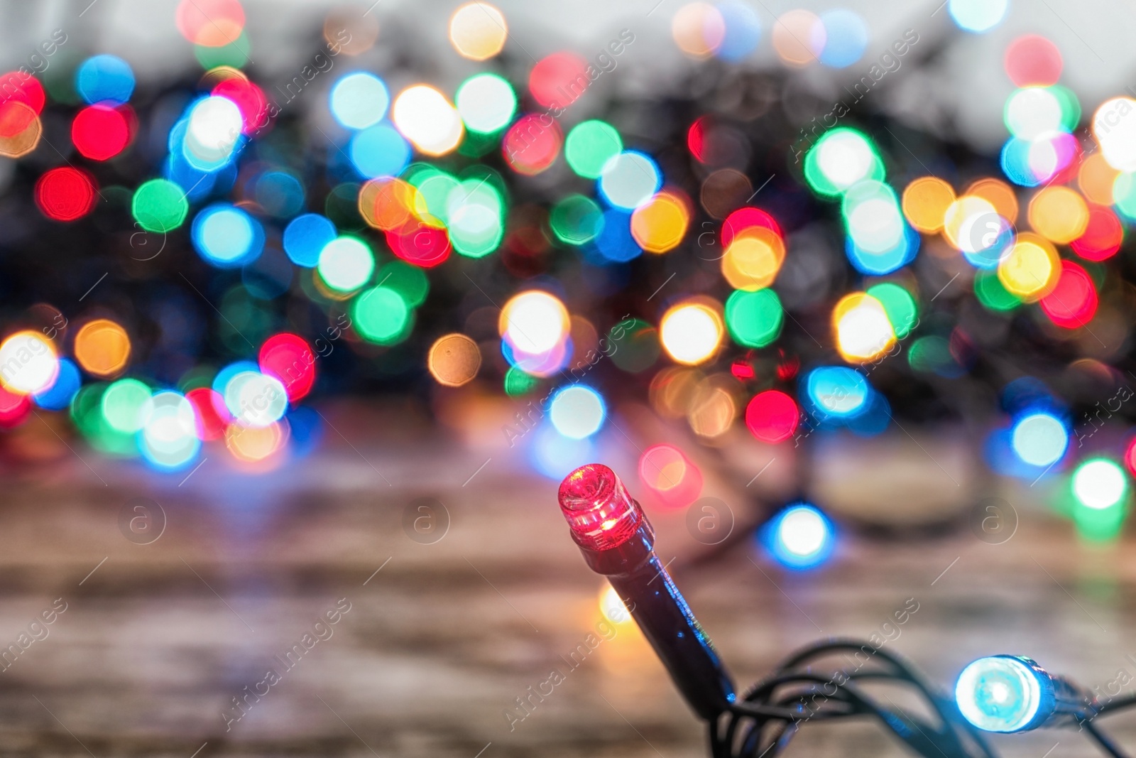 Photo of Glowing colorful Christmas lights on table, closeup