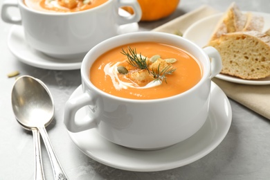 Photo of Tasty creamy pumpkin soup with croutons, seeds and dill in bowl on light grey table