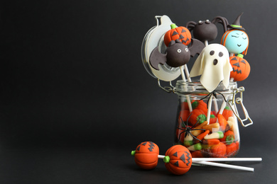 Photo of Delicious Halloween themed cake pops on black background, space for text