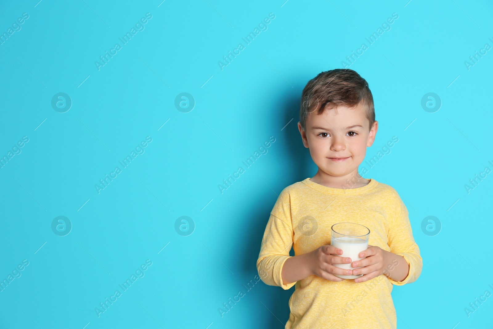 Photo of Cute little boy with glass of milk on color background