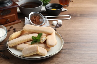 Photo of Tasty cookies and other tiramisu ingredients on wooden table, space for text