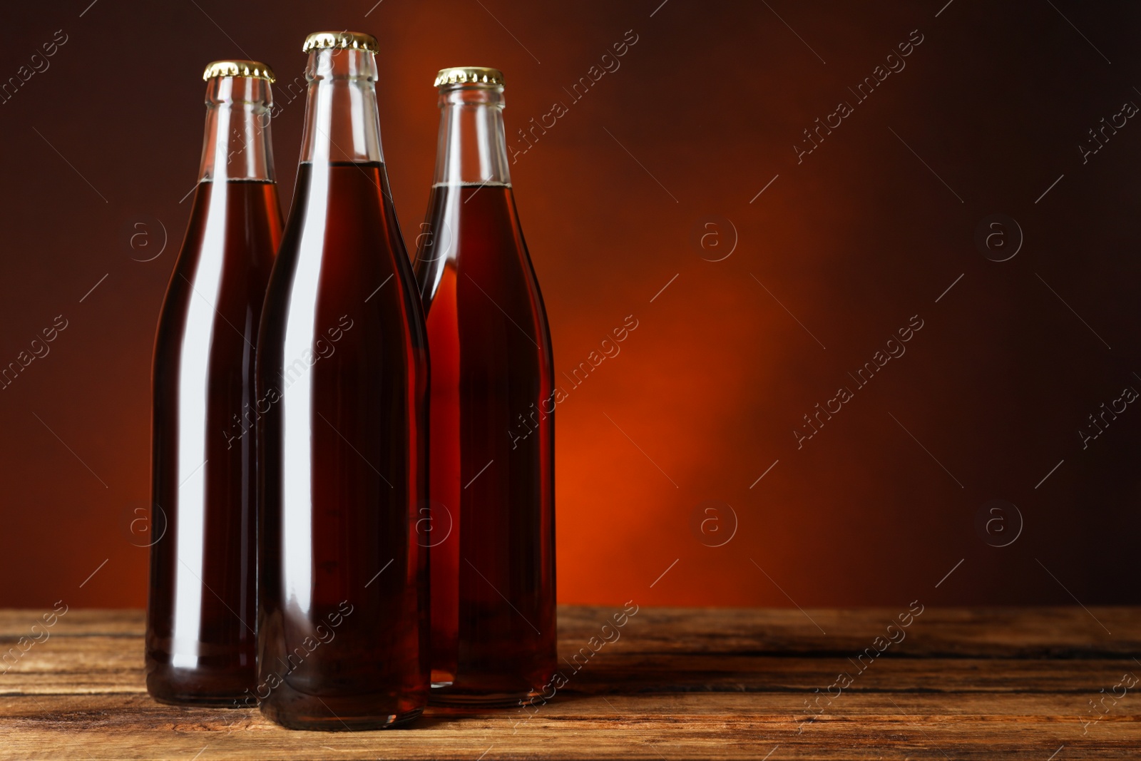 Photo of Bottles of delicious kvass on wooden table. Space for text