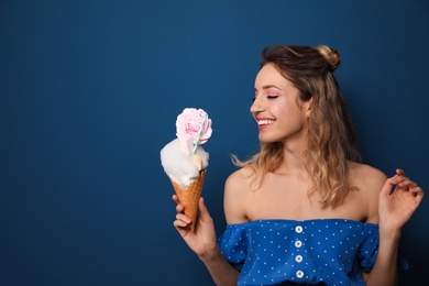 Portrait of young woman holding cotton candy dessert on blue background, space for text