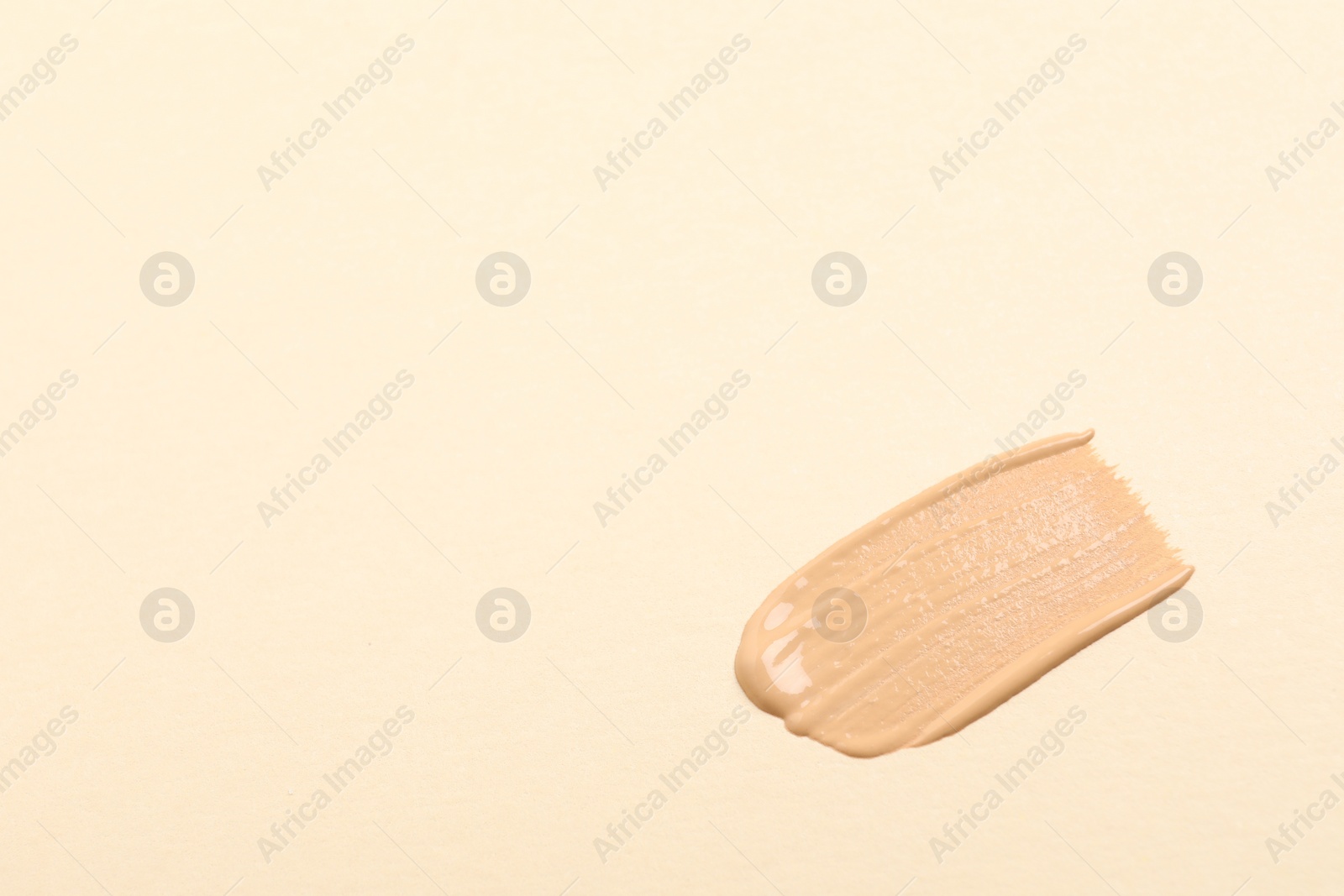 Photo of Smear of skin foundation on beige background, top view. Space for text