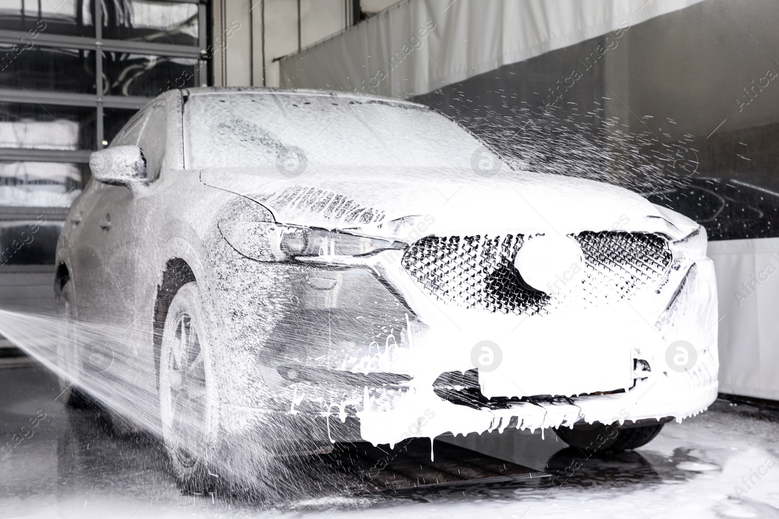 Photo of Cleaning automobile with high pressure water jet at car wash