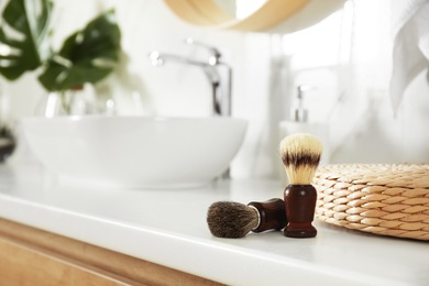 Photo of Shaving brushes on light countertop in bathroom