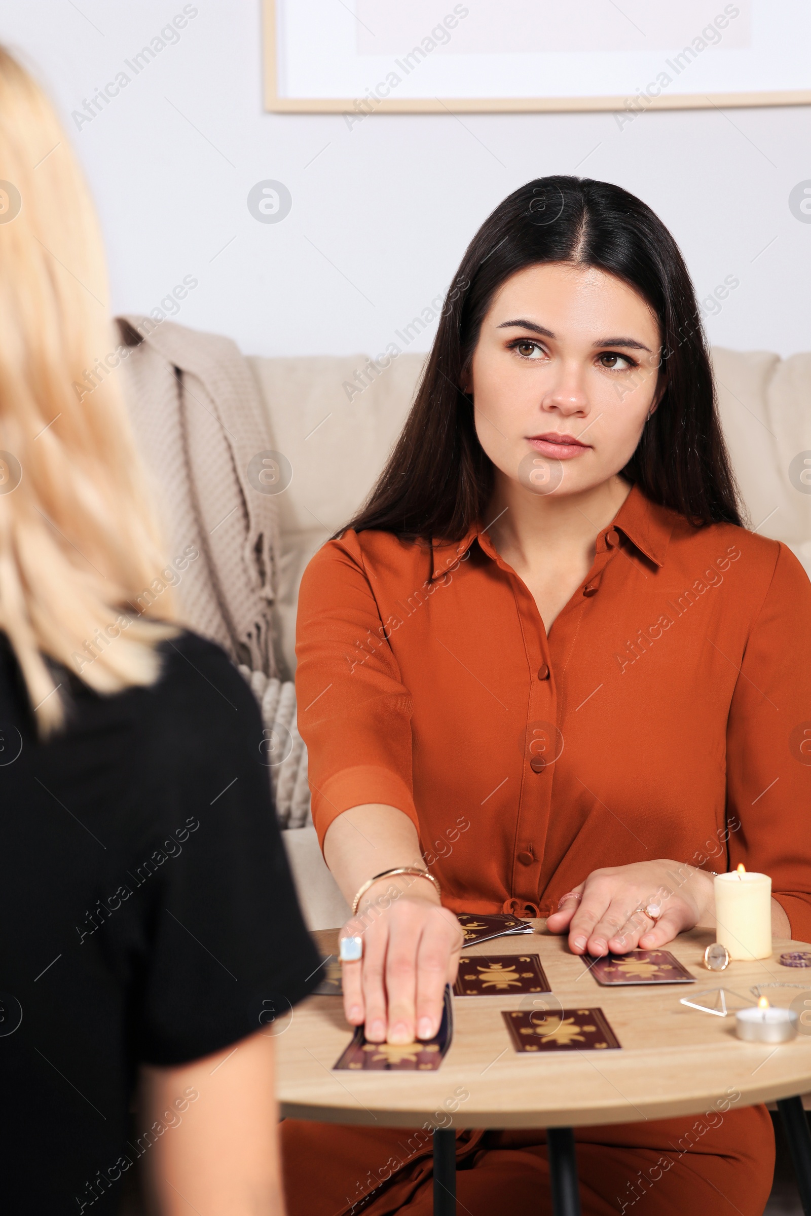 Photo of Soothsayer predicting future with tarot cards at table in room