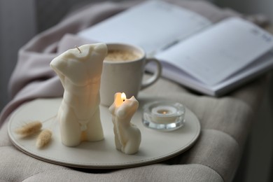 Photo of Beautiful body shaped candles and cup of hot drink on bench indoors