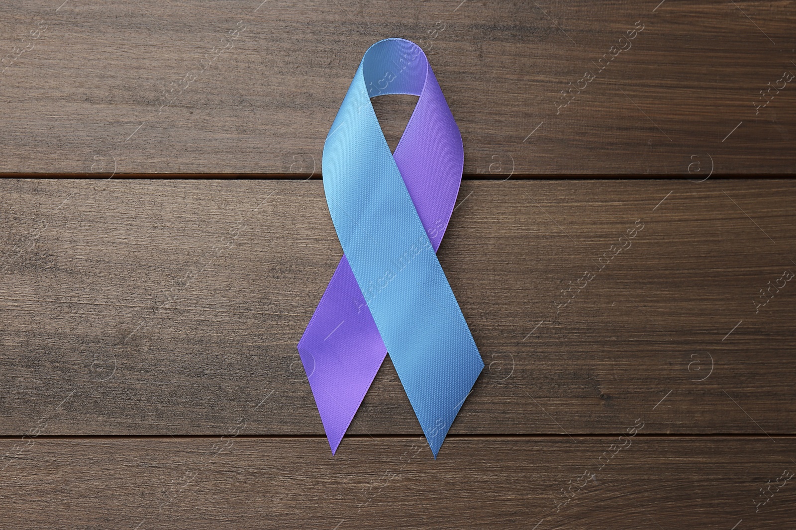 Image of World Arthritis Day. Blue and purple awareness ribbon on wooden background, top view