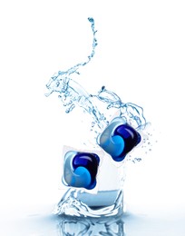 Image of Laundry capsules falling into water on white background. Detergent pods