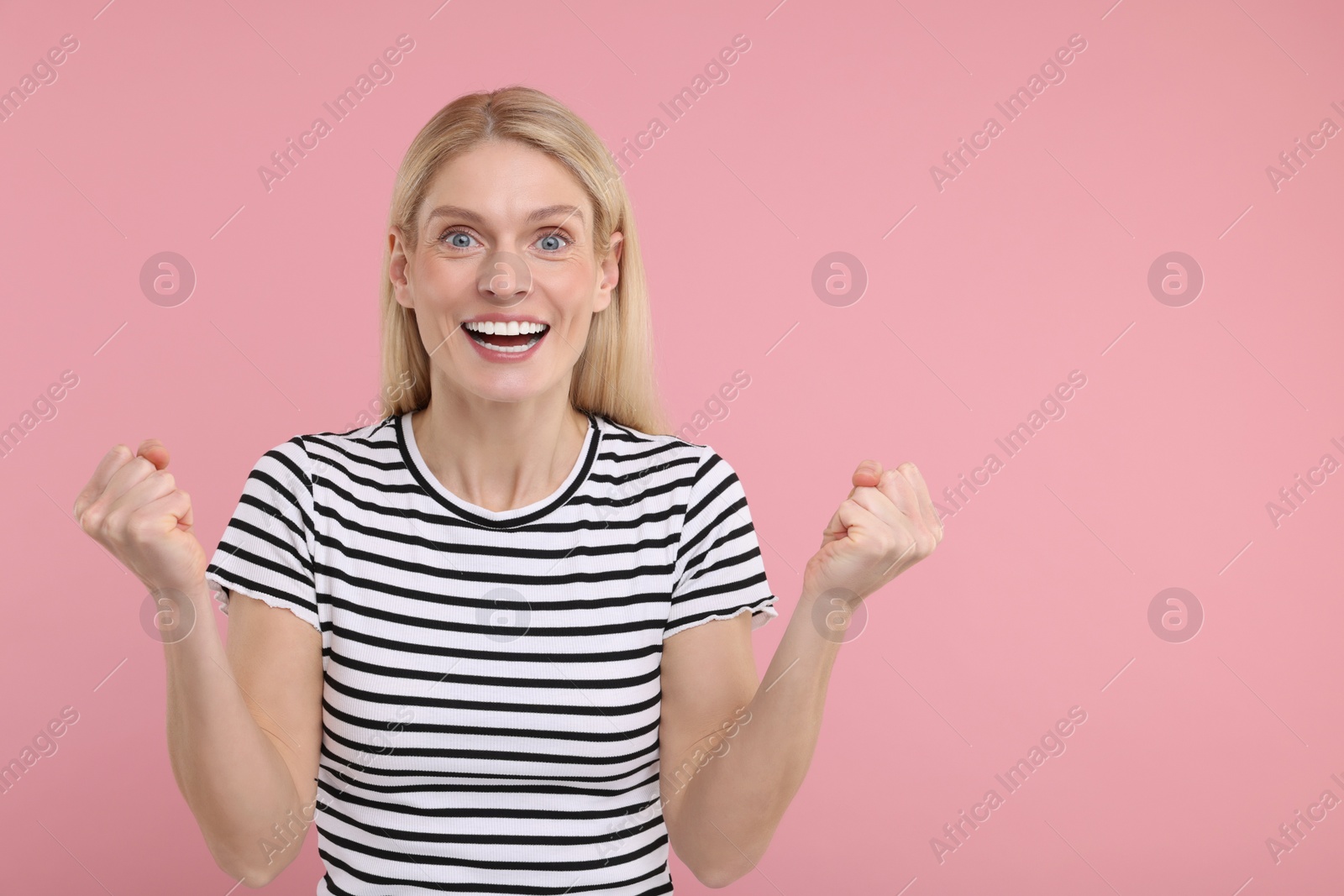 Photo of Portrait of happy surprised woman on pink background, space for text