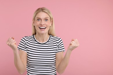 Photo of Portrait of happy surprised woman on pink background, space for text