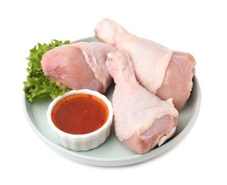 Photo of Fresh marinade, raw chicken drumsticks and lettuce isolated on white
