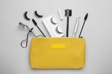 Flat lay composition with fake eyelashes, brushes and tools on light grey background