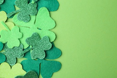 Photo of St. Patrick's day. Decorative clover leaves on green background, top view. Space for text