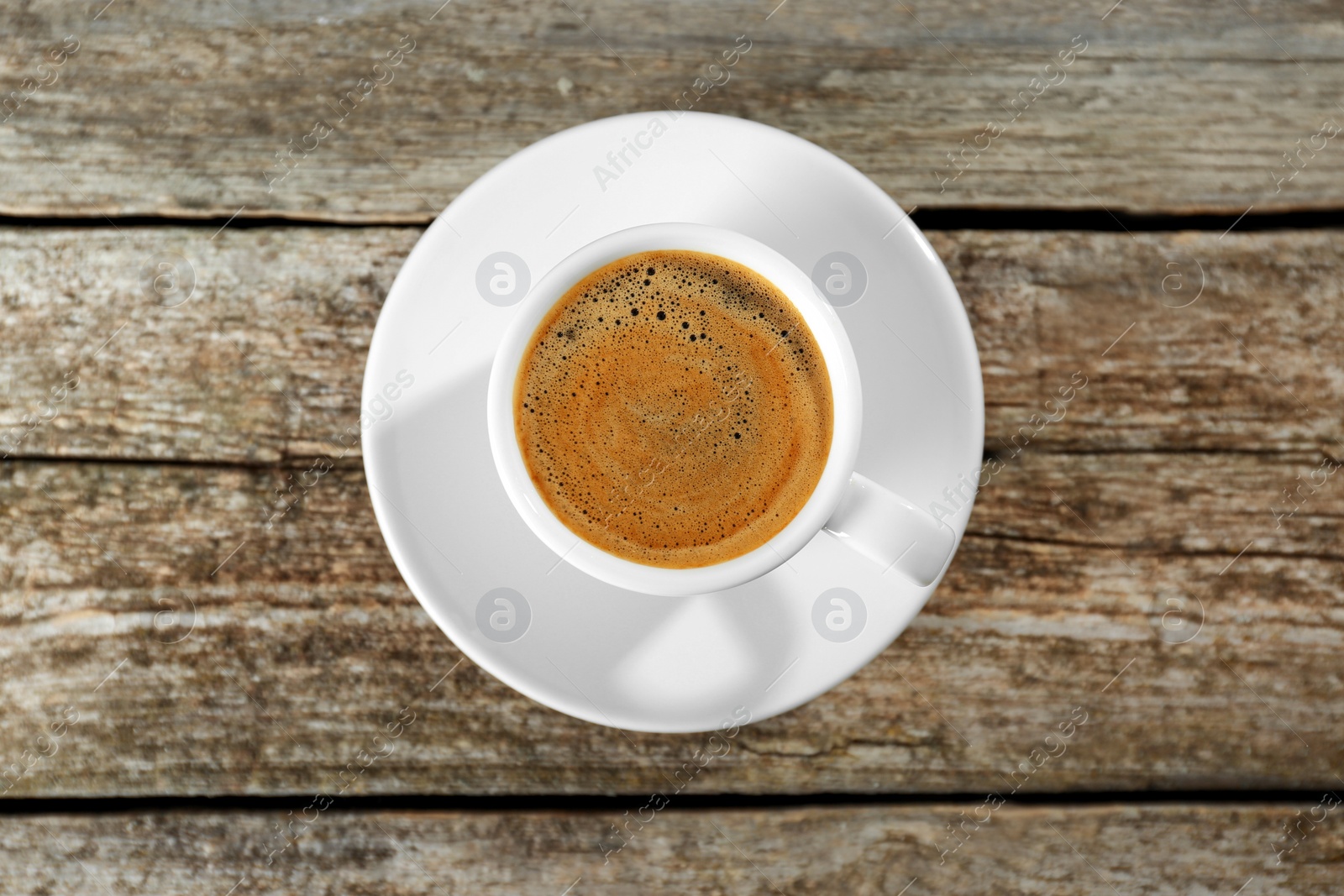 Photo of Cup of tasty coffee on wooden table, top view