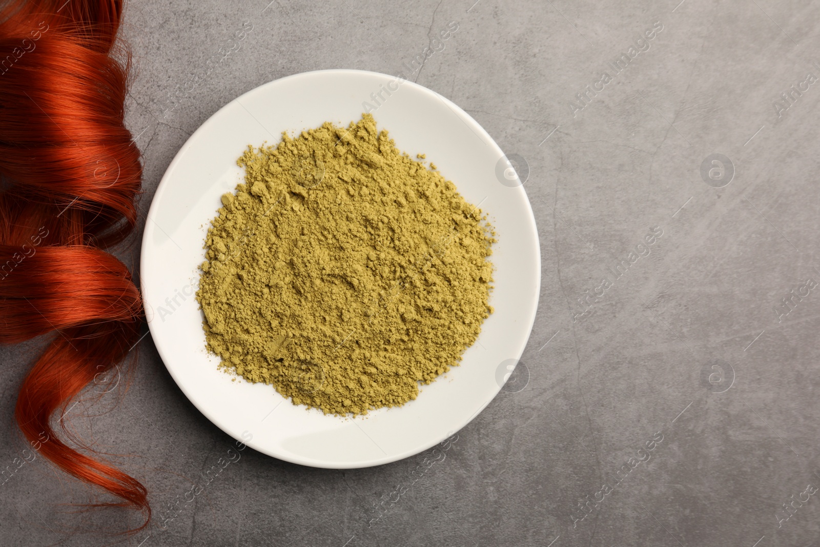 Photo of Henna powder and red strand on grey table, flat lay with space for text. Natural hair coloring