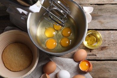 Making dough. Raw eggs in bowl of stand mixer and ingredients on wooden table, flat lay
