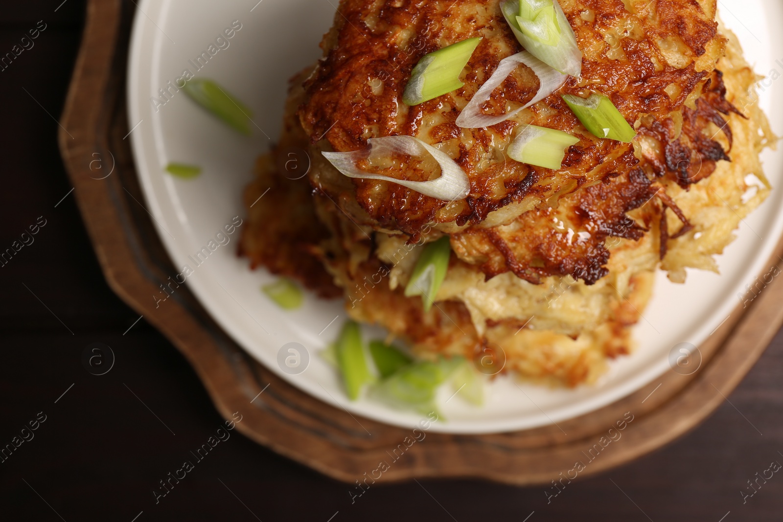 Photo of Tasty parsnip cutlets with green onion on wooden table, top view