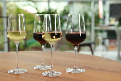 Photo of Glasses with different wines on table against blurred background