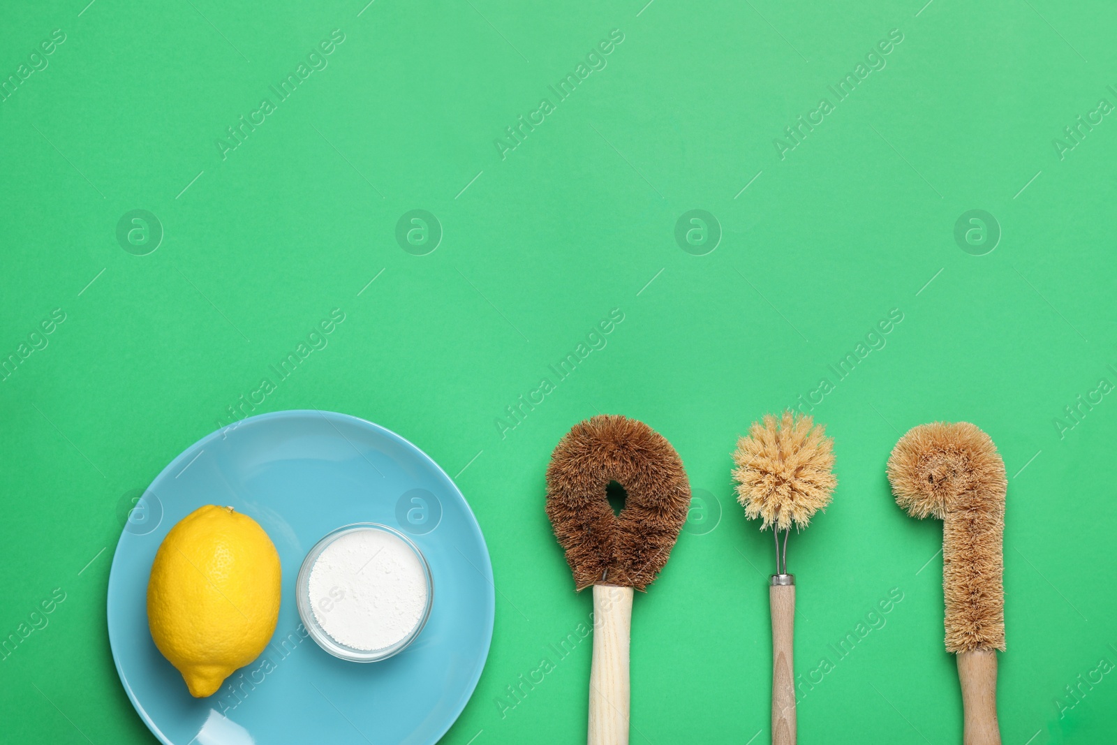 Photo of Cleaning supplies for washing dishes on green background, flat lay