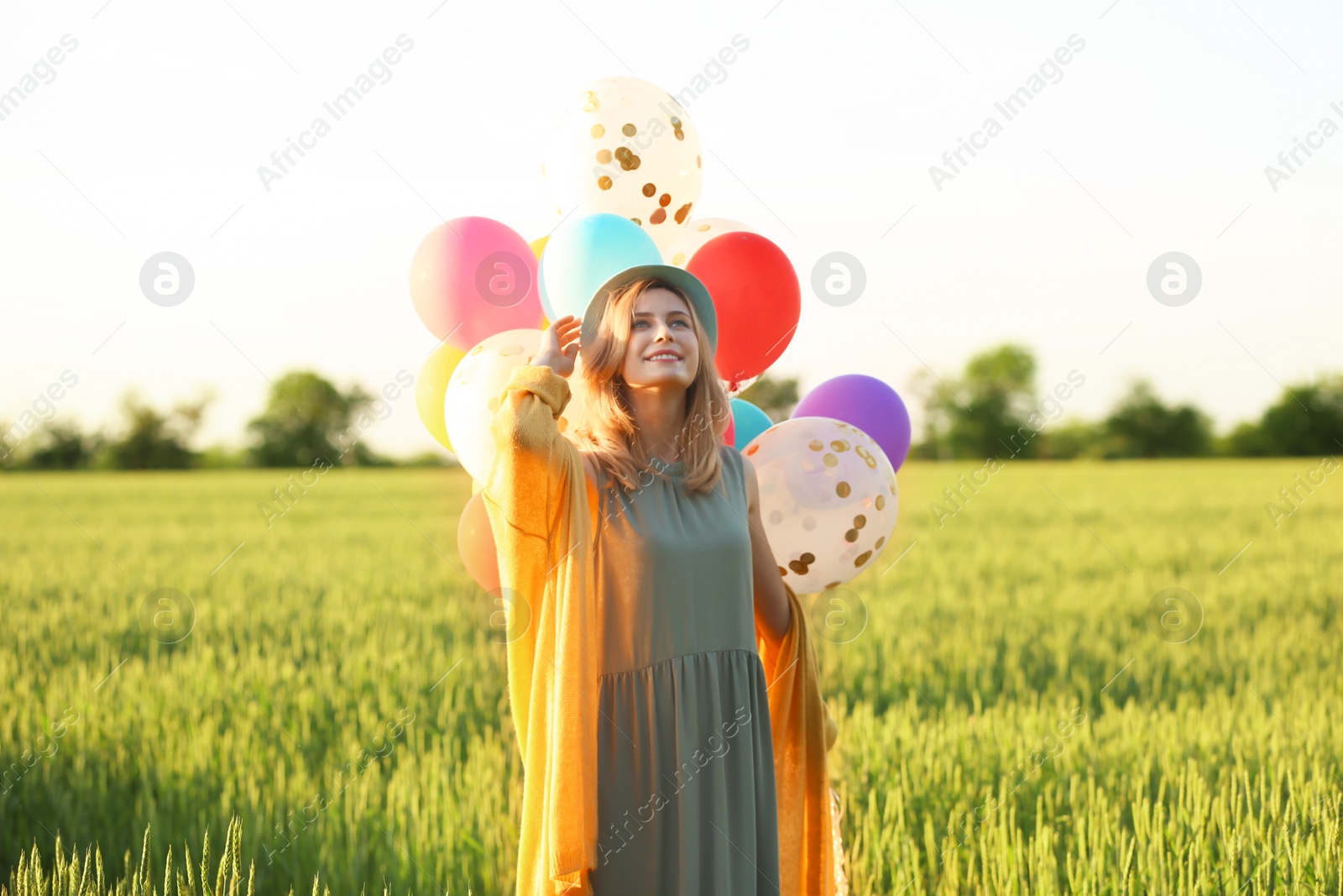 Photo of Young woman with colorful balloons in field on sunny day