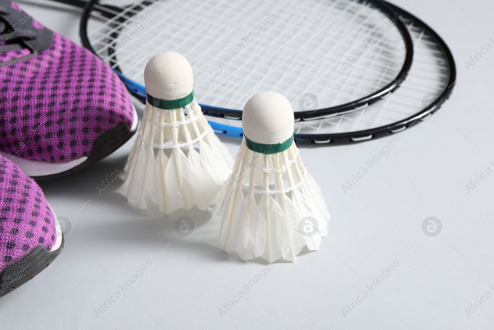 Photo of Feather badminton shuttlecocks, rackets and sneakers on gray background