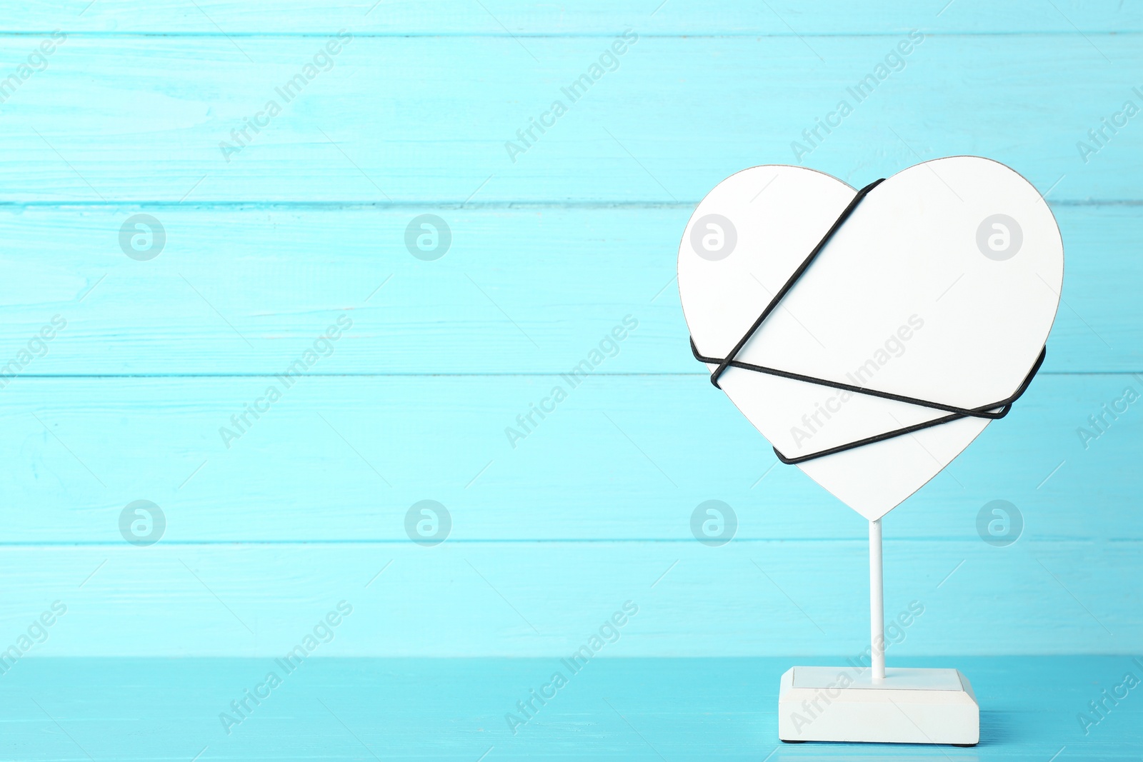 Photo of Decorative heart on stand against color background, space for text