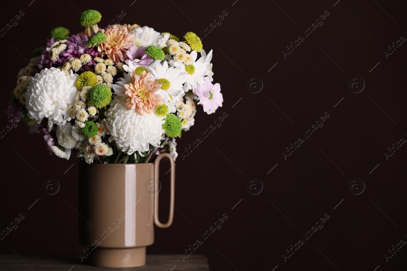 Photo of Bouquet of beautiful chrysanthemum flowers on table against dark background, space for text