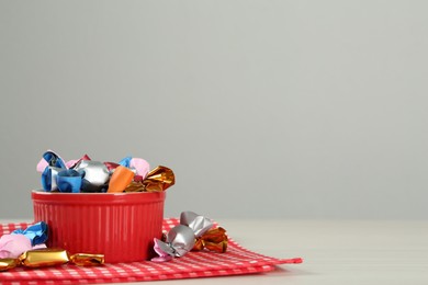 Photo of Candies in colorful wrappers on light table, space for text