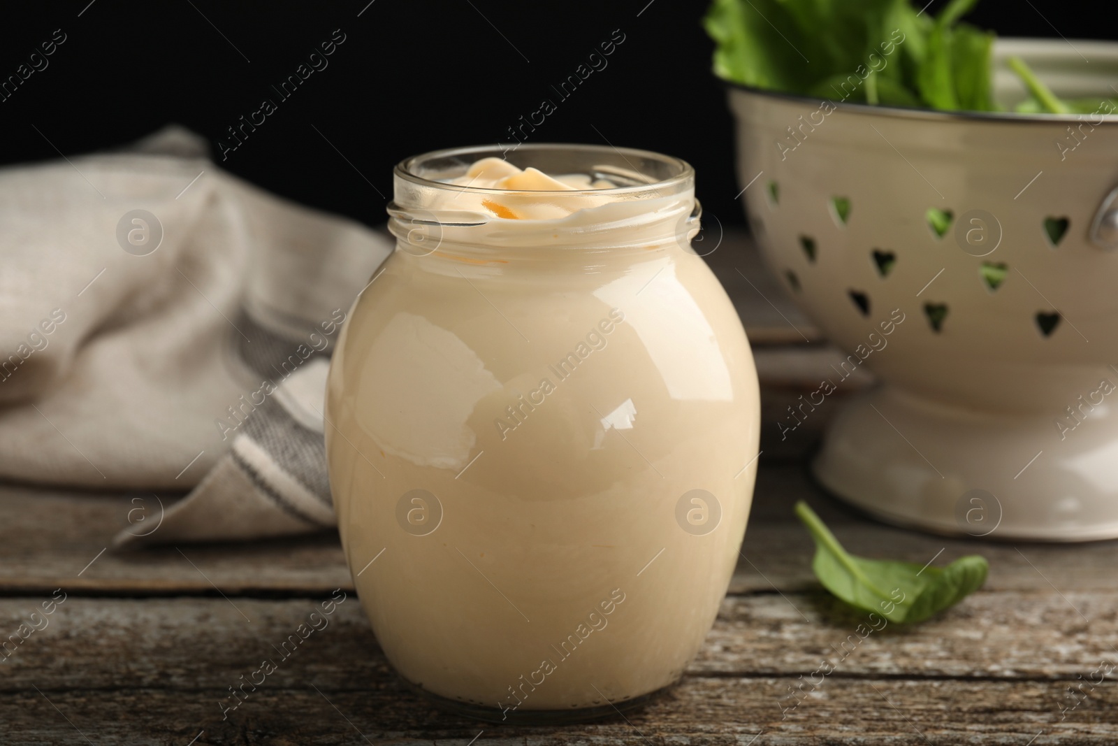 Photo of Jar of delicious mayonnaise and fresh spinach on wooden table