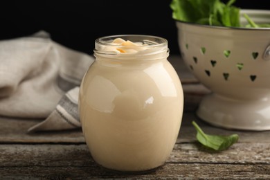 Photo of Jar of delicious mayonnaise and fresh spinach on wooden table
