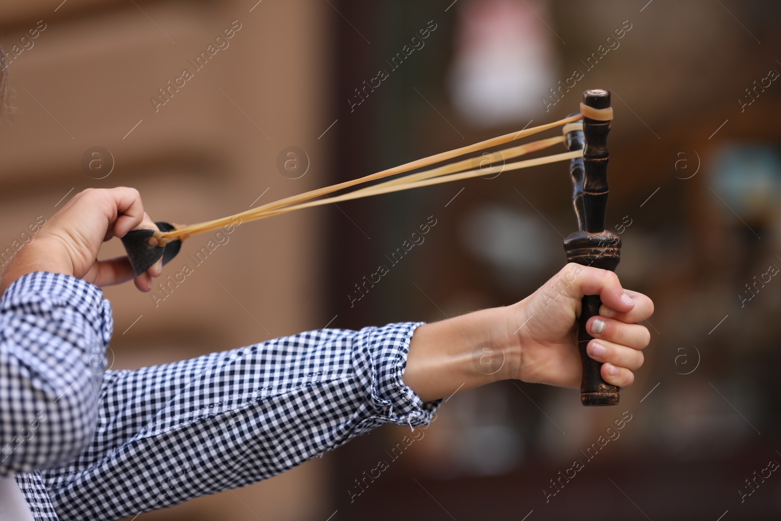 Photo of Little boy playing with slingshot outdoors, closeup