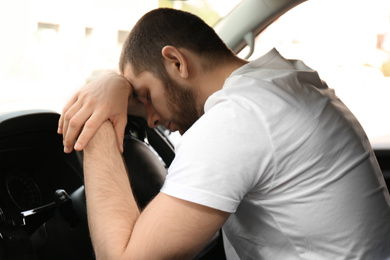 Tired man sleeping on steering wheel in his car