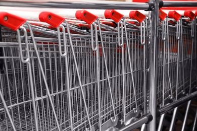 Photo of Many empty shopping carts in supermarket, closeup