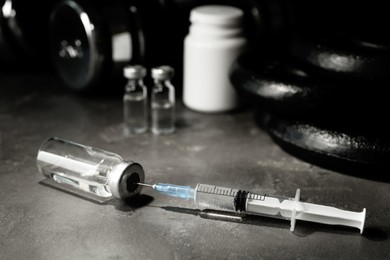 Vial and syringe with drug near sports equipment on grey table. Doping control