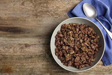 Photo of Fried minced meat, spoon and napkin on wooden table, top view. Space for text