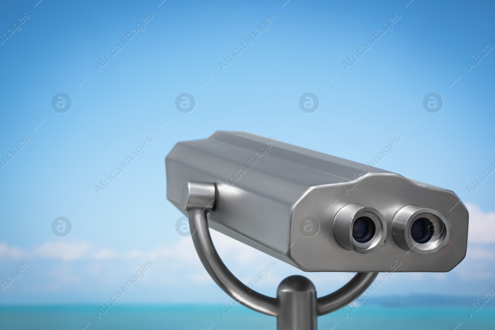 Photo of Metal tower viewer installed near sea. Mounted binoculars