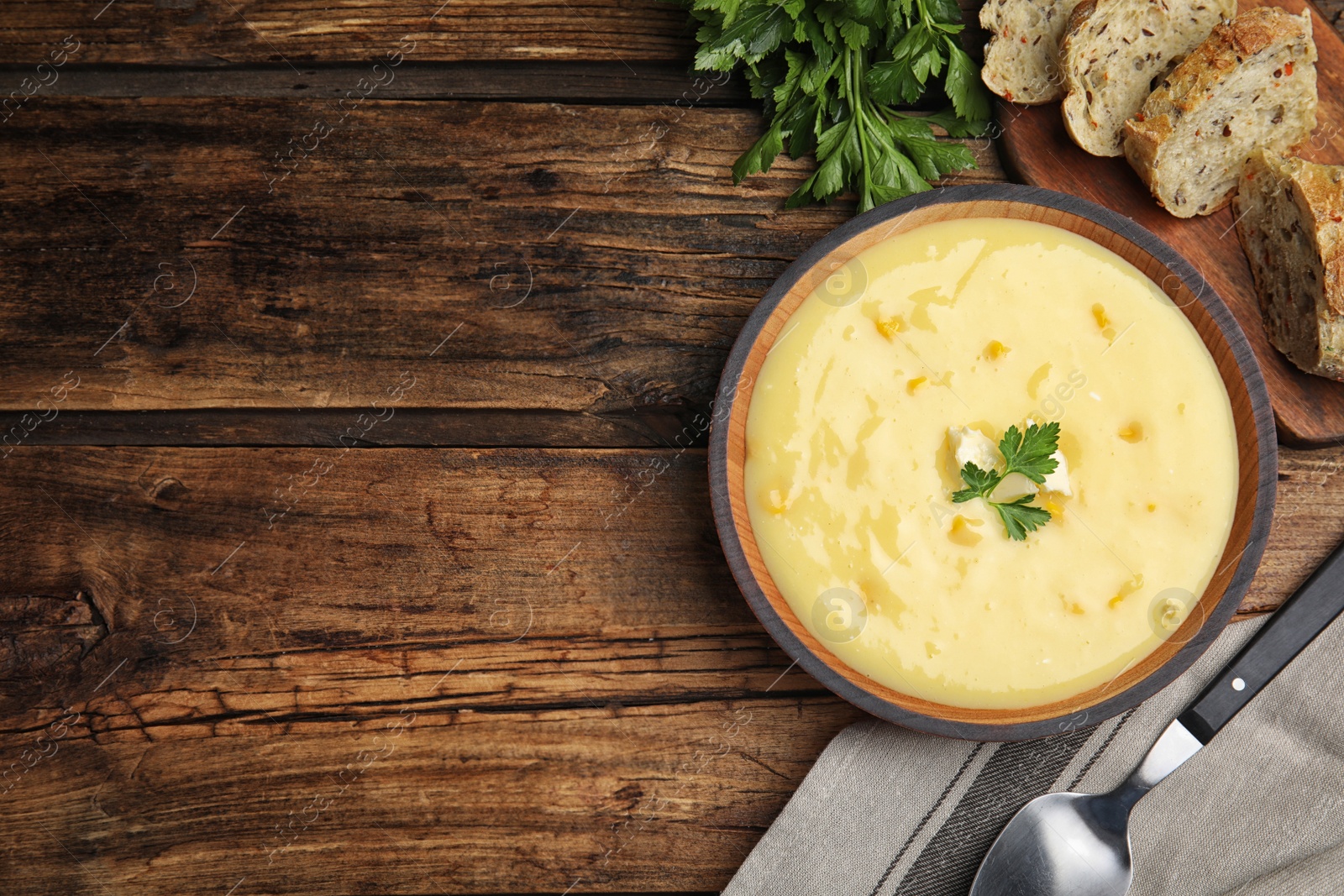 Photo of Delicious corn cream soup served on wooden table, flat lay. Space for text