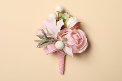 Stylish pink boutonniere on beige background, top view