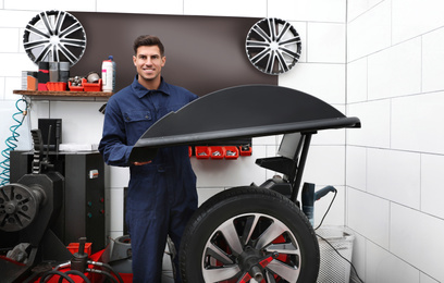 Photo of Man working with wheel balancing machine at tire service