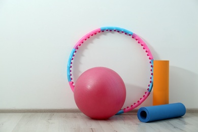 Photo of Hula hoop, fitness ball and mats near light wall in gym