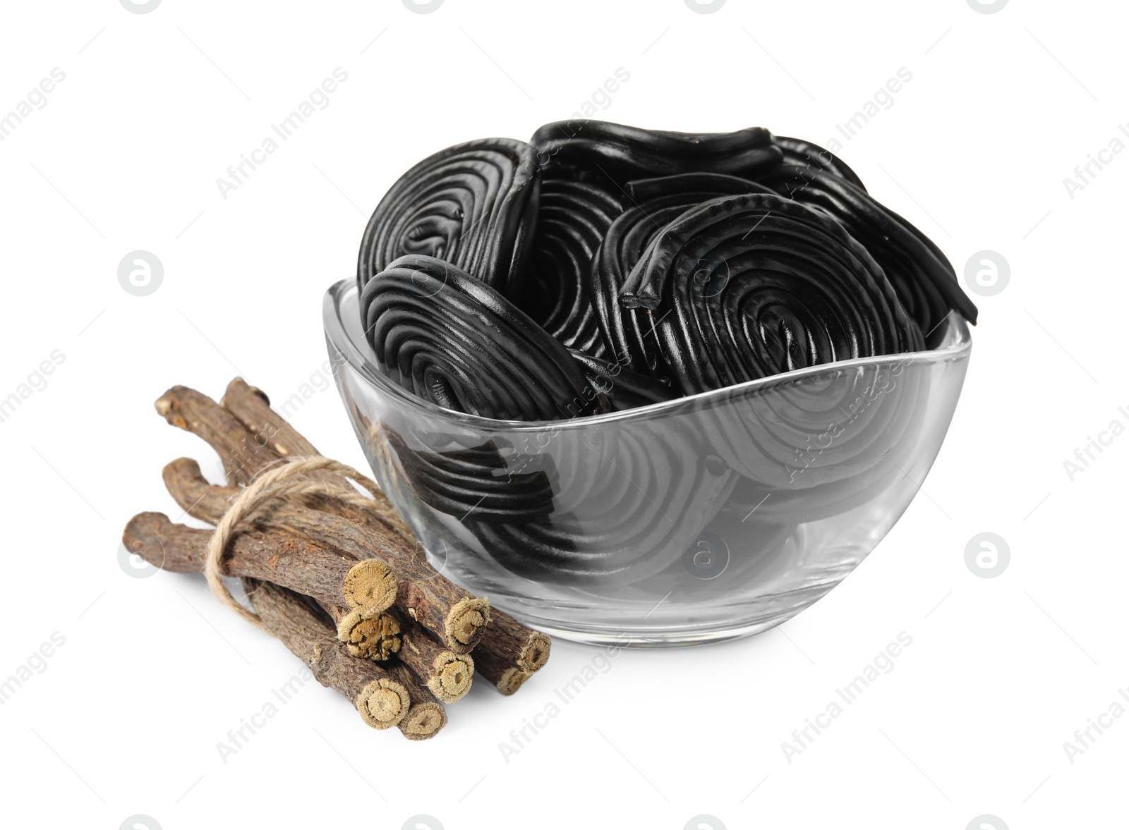 Photo of Tasty black candies and dried sticks of liquorice root on white background