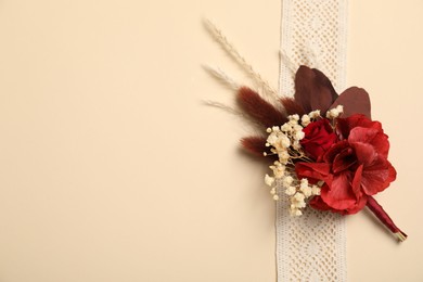 Photo of Stylish red boutonniere and ribbon on beige background, top view. Space for text