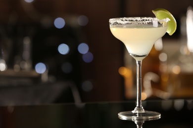 Photo of Delicious cocktail with lime and sugar on bar counter. Space for text