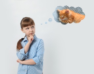 Image of Little girl on light background dreaming about cute kitten